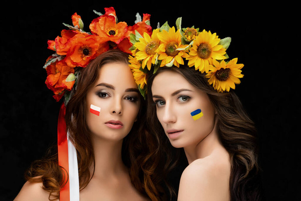 Two beautiful girls in flower wreaths of red poppy and yellow sunflower with ribbons. Concept Poland and Ukraine. Friendship and help Ukraine. Stop the war. High quality photo - Foto, Imagem