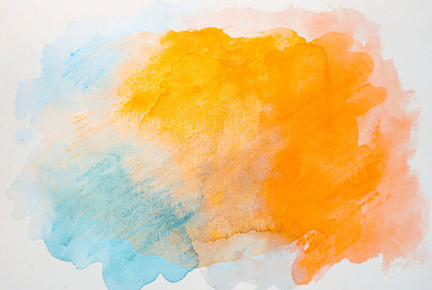 Abstraktes oranges, gelbes und bläuliches Aquarell auf weißem Hintergrund, buntes Aquarell spritzt auf das Papier, abstrakte gemalte Illustration Dekoration Hintergrund - Foto, Bild