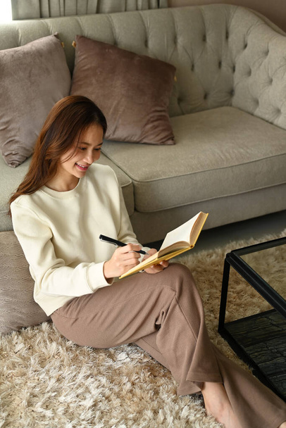 Kellemes fiatal nő, aki otthon pihen és a naplóját írja. Szabadidős tevékenység, pozitív hangulat koncepció. - Fotó, kép