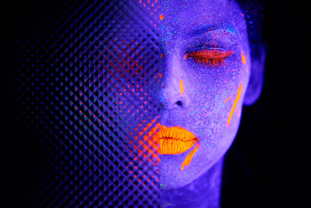 The beauty of the surreal. a young woman posing with neon paint on her face - Valokuva, kuva
