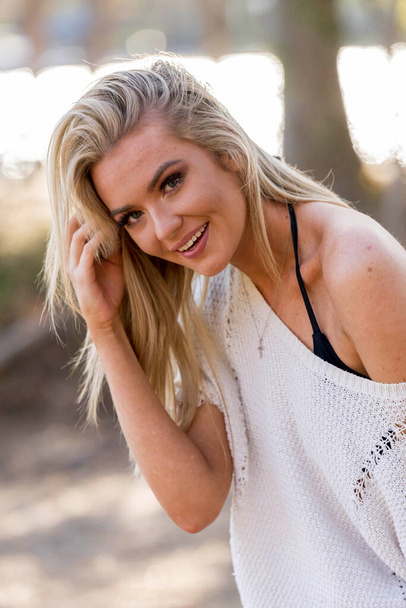 A gorgeous blonde bikini model poses outdoors near a lake while enjoying the summer weather. - Foto, imagen