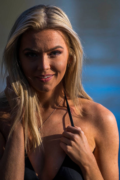 A gorgeous blonde bikini model poses outdoors near a lake while enjoying the summer weather. - Foto, immagini