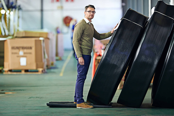 Our product cant be beaten. a man standing next to large coils of plastic in a large warehouse - Фото, изображение