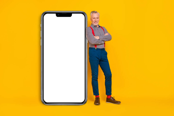 Full length body size view of attractive cheery grey-haired man folded arms copy space ad isolated over vivid yellow color background. - 写真・画像