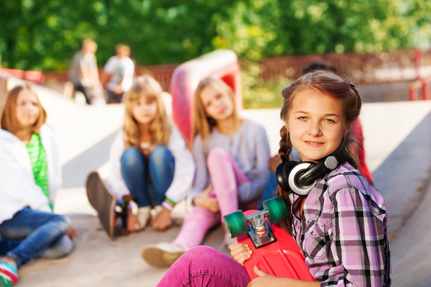 Girl holds skateboard wearing headphones - Zdjęcie, obraz
