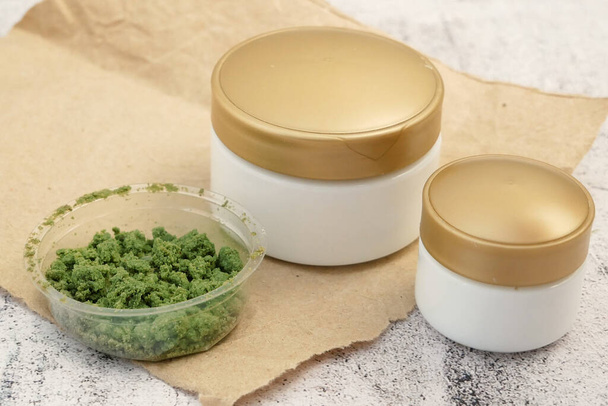 Crème de cannabis cosmétique en dose avec plante de marijuana sur fond en bois. Concept cosmétique cannabis. - Photo, image