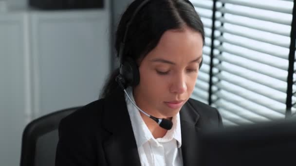 Competent african american female operator working on computer and while talking with clients. Concept relevant to both call centers and customer service offices. - Imágenes, Vídeo