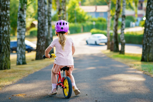 Little preschool girl with helmet running with balance bike on summer day. Happy child driving, biking with bicycle, outdoor activity. Happiness, childhood. Summer activity for children - Valokuva, kuva
