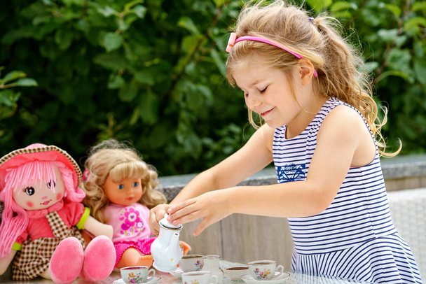 Little preschool girl playing with dolls. Happy excited child play tea party with toys. Role games for children, activity for one person. Role game for small children - Photo, image