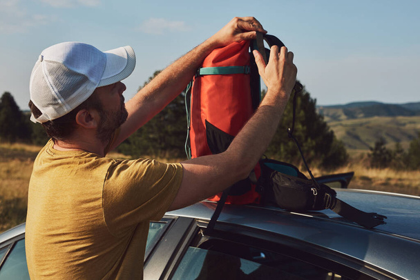 Человек кемпинг и походы на природе, распаковка из автомобиля на открытом воздухе, отдых и хобби. - Фото, изображение