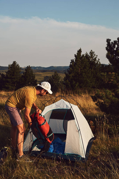 Homem acampar na natureza, desempacotando e embalando tenda pequena ao ar livre, recreação e hobbies. - Foto, Imagem