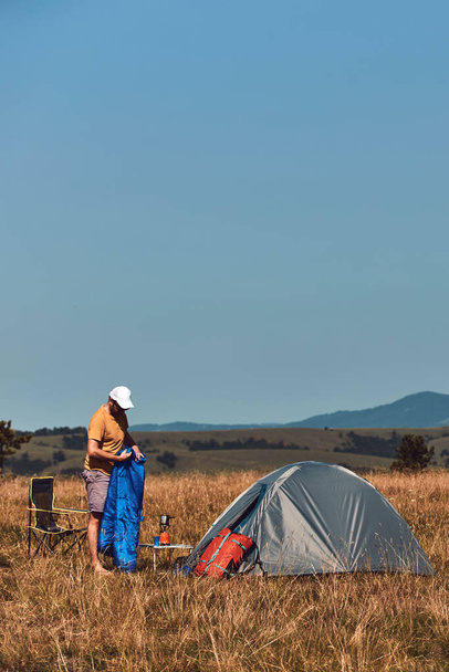 Homme camping dans la nature, déballage et emballage petite tente à l'extérieur, loisirs et passe temps. - Photo, image
