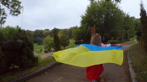 Ukrainan tyttö lapsi kulkee lippu käsissään. Lapsi iloitsee Ukrainan lipusta. - Materiaali, video