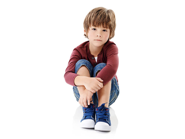 Where is everyone. Studio shot of a cute little boy hugging his knees against a white background - Foto, Imagen