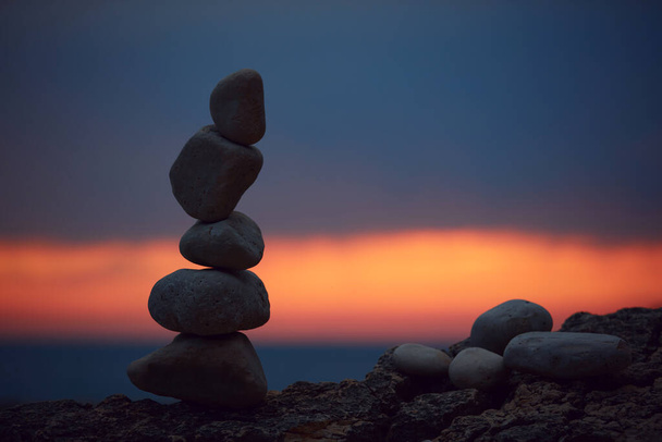 Silhouette of balanced zen stones on the ocean beach at sunset sunrise time. - Photo, Image