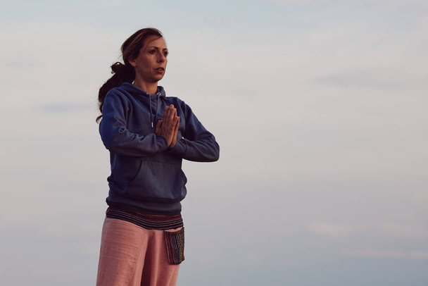 Женщина практикует йогу на открытом воздухе во время восхода солнца. - Фото, изображение