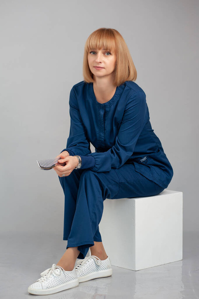 schöne junge Frau in weißem Hemd und blauer Jeans, die auf einem Stuhl sitzt und in die Kamera schaut - Foto, Bild