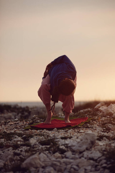 Frau praktiziert Yoga im Freien bei Sonnenuntergang. - Foto, Bild