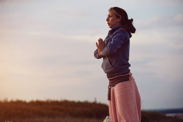 Nő gyakorló jóga szabadban naplementekor napkelte idő. - Fotó, kép