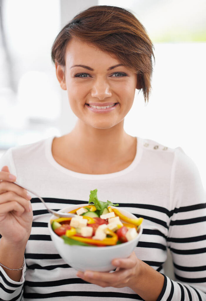 Excited about my salad. Portrait of a cheerful young woman eating salad - Foto, afbeelding