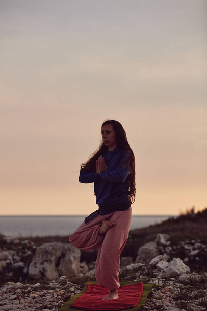 Donna che pratica yoga all'aperto al tramonto ora dell'alba. - Foto, immagini