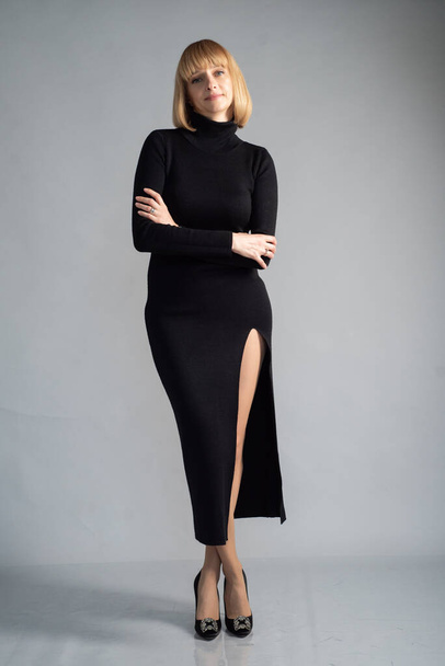 bela mulher loira em vestido preto posando no fundo cinza - Foto, Imagem