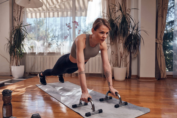 Pretty woman working out at home. Adult lady with beautiful shaped body exercising in the apartment. - Zdjęcie, obraz