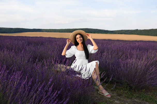 Beautiful young woman sitting in lavender field - Photo, Image
