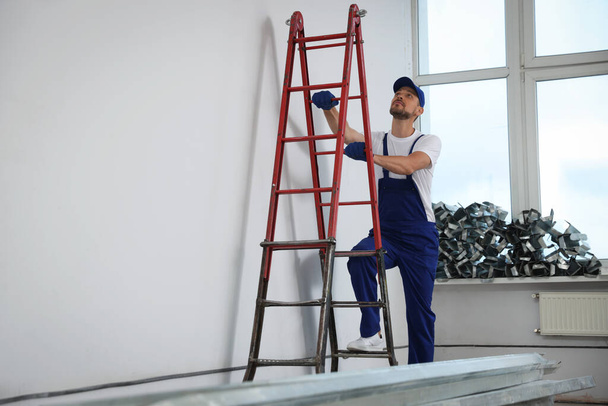 Construction worker climbing up stepladder in room prepared for renovation - Φωτογραφία, εικόνα