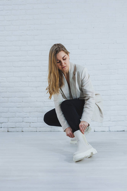 Fénykép egy fiatal nőről fehér csizmában és alkalmi ruhában. Valódi bőrből készült női téli cipők új kollekciója. - Fotó, kép
