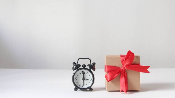 Gift box with black alarm clock on white background. - Foto, Imagen