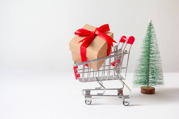 Gift box with miniature shopping cart on white background. - Photo, image