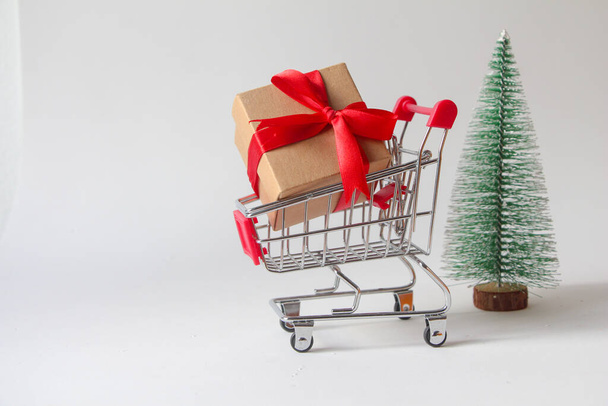 Gift box with miniature shopping cart on white background. - Photo, Image