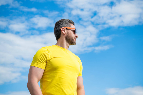 guy in yellow shirt and sunglasses outdoor on sky background with copy space. - Foto, Bild
