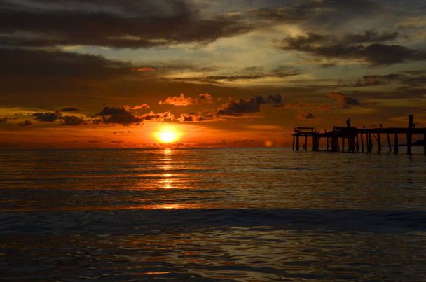 Thailand, Koh Kood Island. Beautiful atmosphere with sunset. Warm sea, wooden pier, sweet and painful feeling of happiness. Beautiful sunset colors, clouds illuminated by the setting sun. Reflection of the sunset on the sea. - Photo, Image