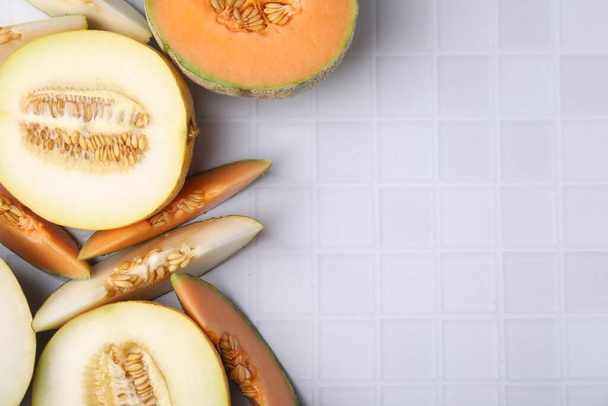 Tasty colorful ripe melons on white checkered table, flat lay. Space for text - Foto, Imagen