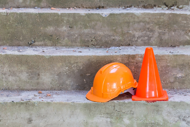 casco de seguridad naranja y cono en el sitio de construcción
 - Foto, imagen