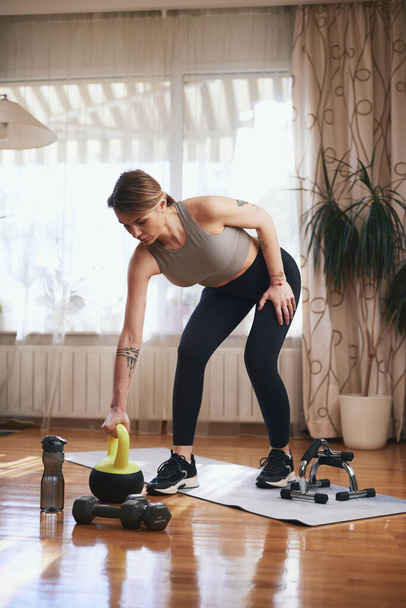 Una mujer guapa haciendo ejercicio en casa. Señora adulta con hermoso cuerpo en forma de ejercicio en el apartamento. - Foto, Imagen
