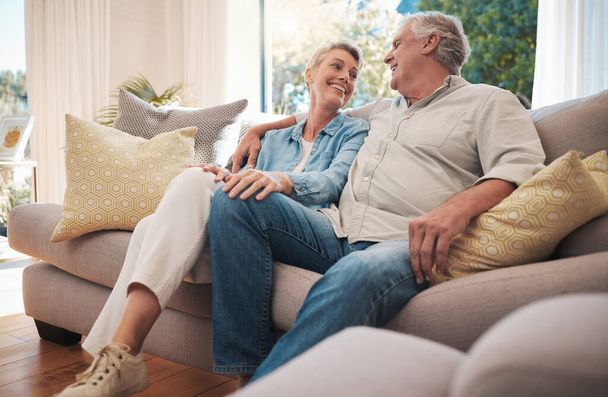 Retirement couple smile on sofa talking about happy marriage, pension and wealth in home or holiday house. Hug, love and care senior woman with man relax on couch together in living room for summer. - Photo, Image
