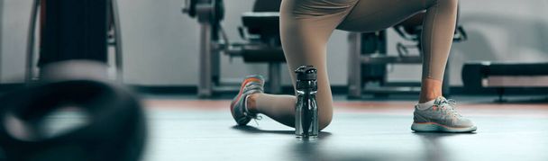 Pretty woman working out in a gym. Adult pretty sporty lady with beautiful shaped body. - Фото, зображення