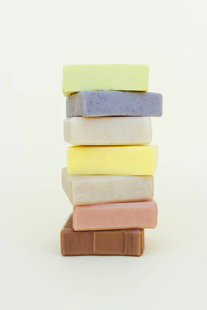 Soap bars stack made with natural herbal ingredients and scented essential oils over light yellow background. Making skincare products at home. Vertical image - Photo, image