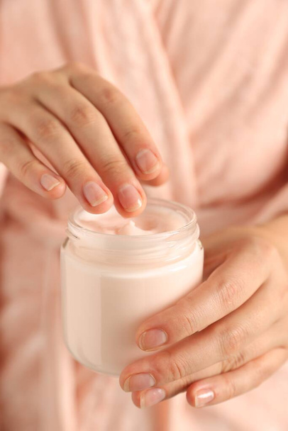 Woman holding jar of hand cream, closeup - Фото, изображение