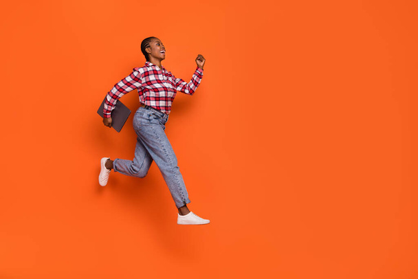 Full body profile photo of energetic pretty girl hurry jumping look empty space isolated on orange color background. - Fotó, kép