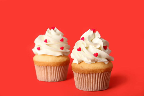 赤い背景のバレンタインデーのためのおいしいカップケーキ - 写真・画像