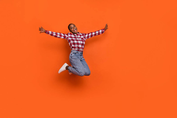 Full length photo of carefree excited girl raise arms flying jumping isolated on orange color background. - Foto, immagini