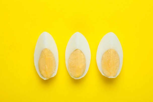Slices of fresh hard boiled egg on yellow background, flat lay - Zdjęcie, obraz