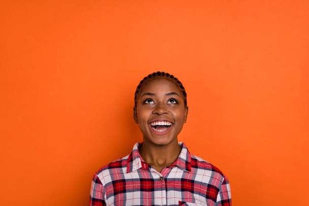 Photo of excited funky lady wear checkered shirt smiling looking up empty space isolated bright vivid orange color background. - Foto, Imagem