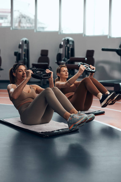 Mujeres guapas haciendo ejercicio en un gimnasio. Señoras adultas con hermosos cuerpos en forma. - Foto, Imagen