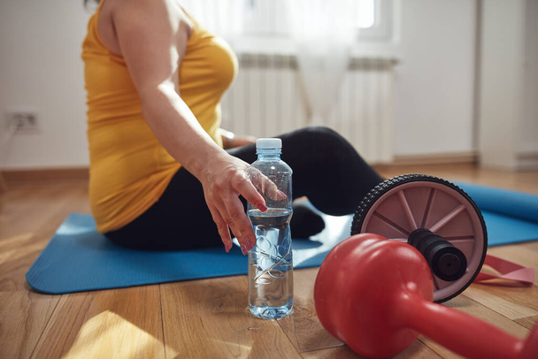Woman training inside the living room, exercising at home, pause and drinking water. - Photo, Image