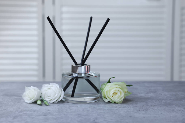Reed air freshener and flowers on grey table indoors - Foto, Bild